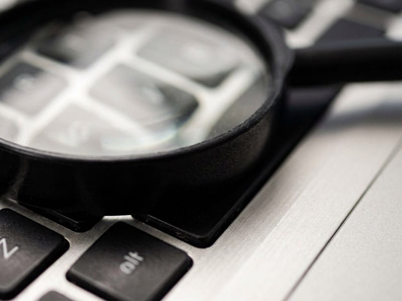 Magnifying glass resting on a laptop keyboard in close-up