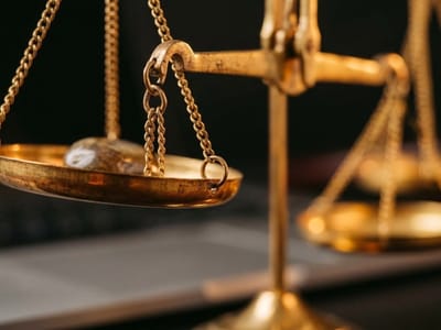 Close-up of brass scales of justice in front of a laptop keyboard