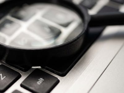 Magnifying glass resting on a laptop keyboard in close-up